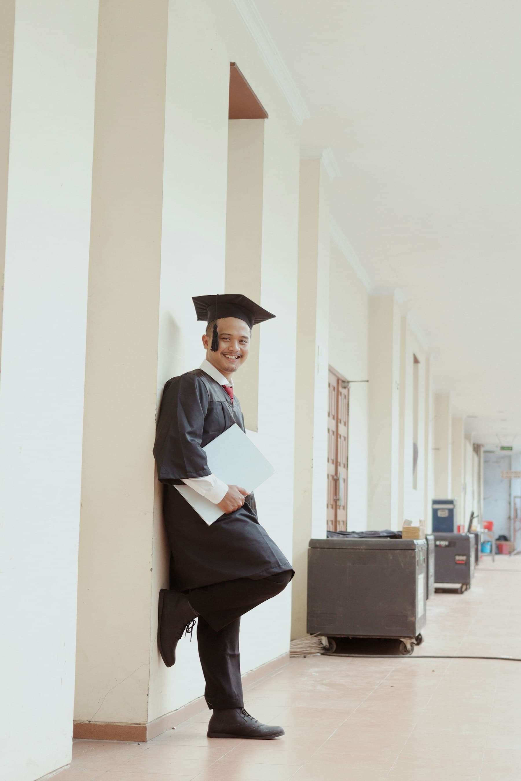 A Southeast Asian graduate holding a diploma folder